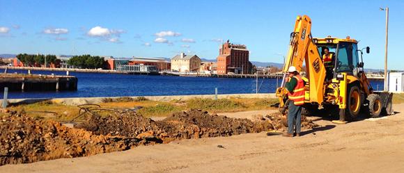 Heavy machinery and piles of dirt on the waterfront showing that the Loop Path construction is underway